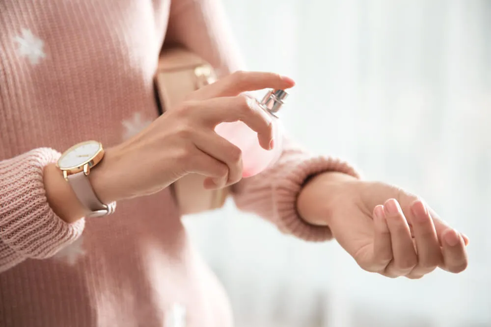 Kobieta spryskująca nadgarstek perfumami